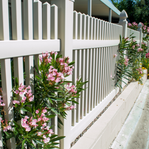 Picture of white wood picket fence with pink flowers